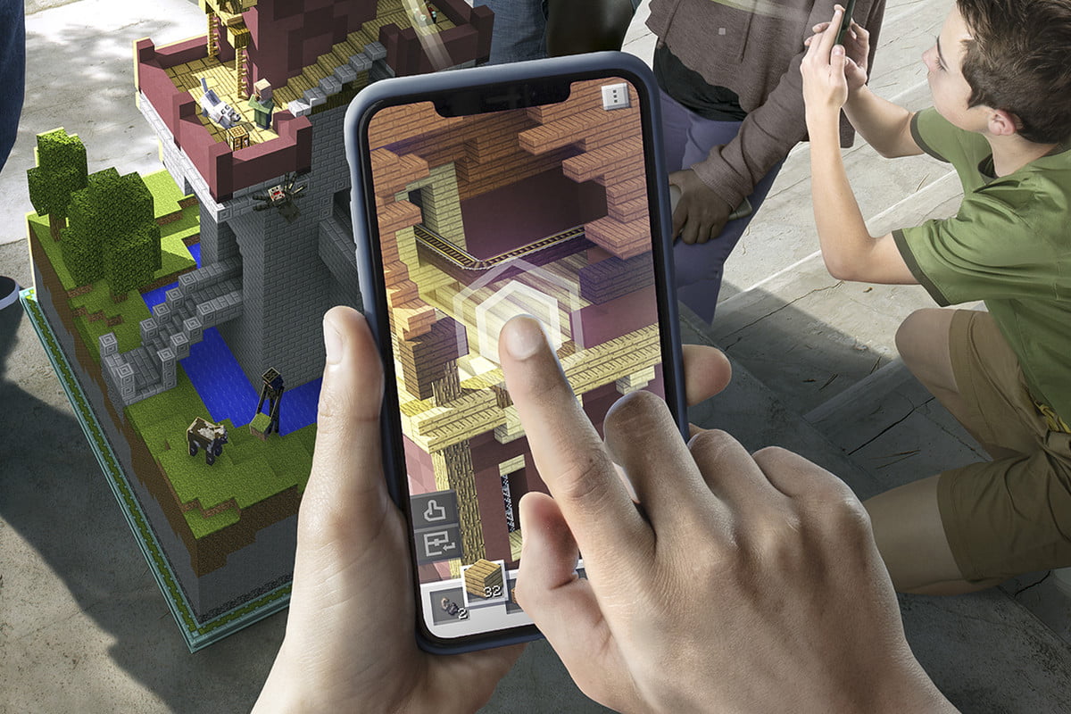 Joueur plaçant un bloc dans l'application sur l'écran du téléphone | Minecraft Earth Key Art